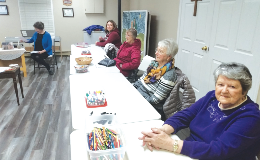 women sitting along a folding table with craft supplies